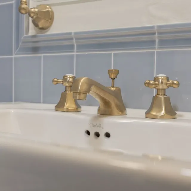 Bathroom renovation detail — brass widespread faucet on blue tile