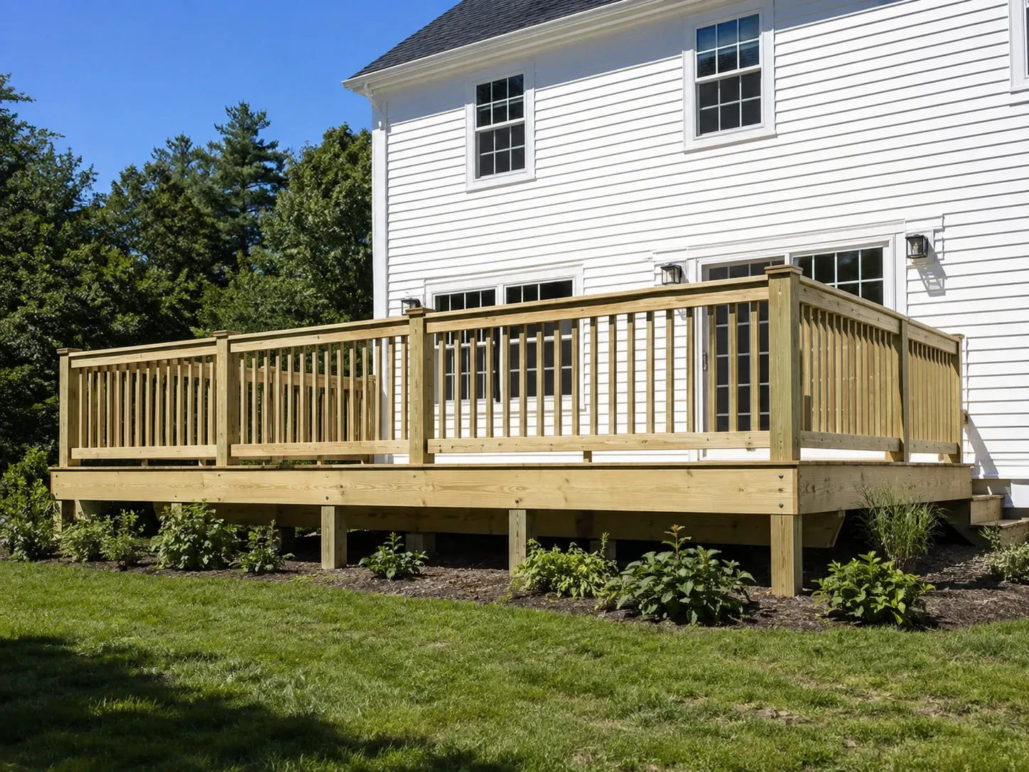 Newly built pressure-treated wood deck with matching railings on a white clapboard New England home