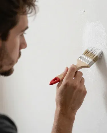 Close-up of a painter’s hand smoothing wallpaper edges in a bright, modern office.