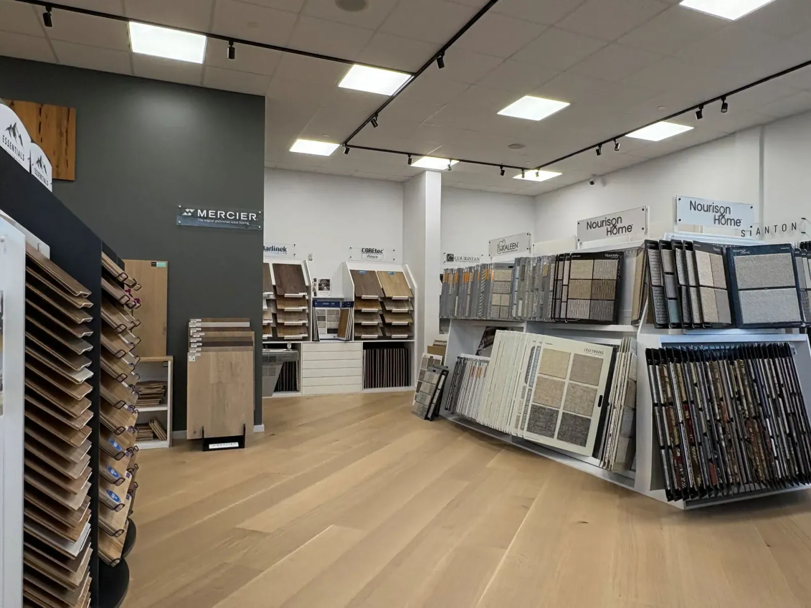 Flooring store showroom with wood plank samples and display racks under bright ceiling lights