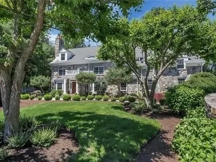 Stone and shingle home with mature landscaping