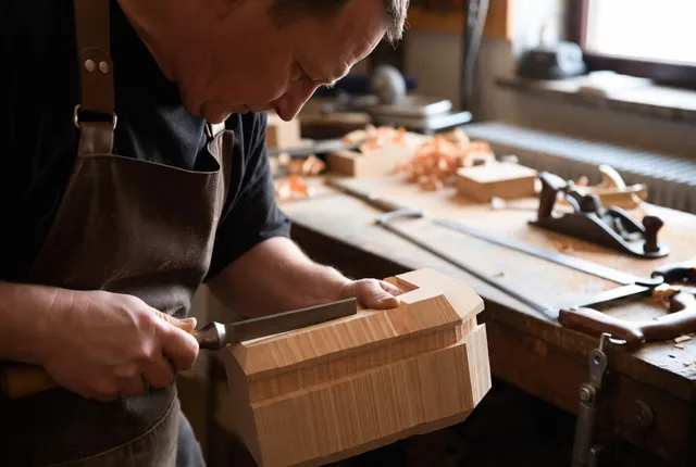 A woodworker hand-planing a dovetailed box at a workbench