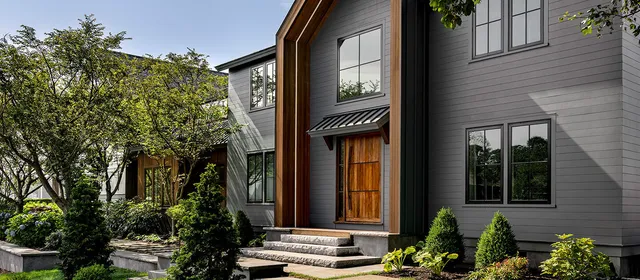 Modern custom outdoor living space with grey siding and wood accents.