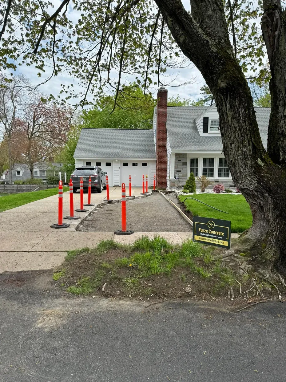 A car is parked in a driveway next to a tree.