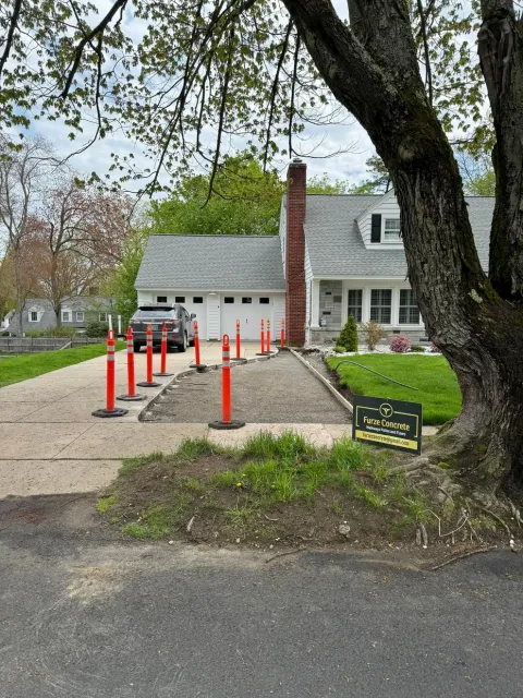 A car is parked in a driveway next to a tree.