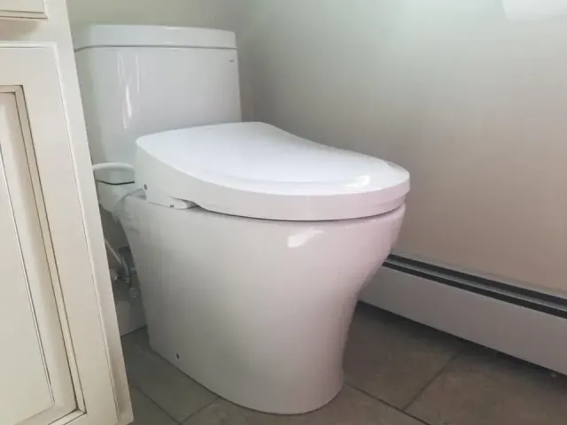 White toilet in a small bathroom with tiled floor and pale walls
