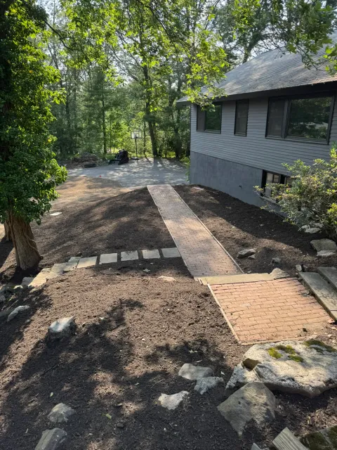 A stone walkway and regraded yard area partway through construction