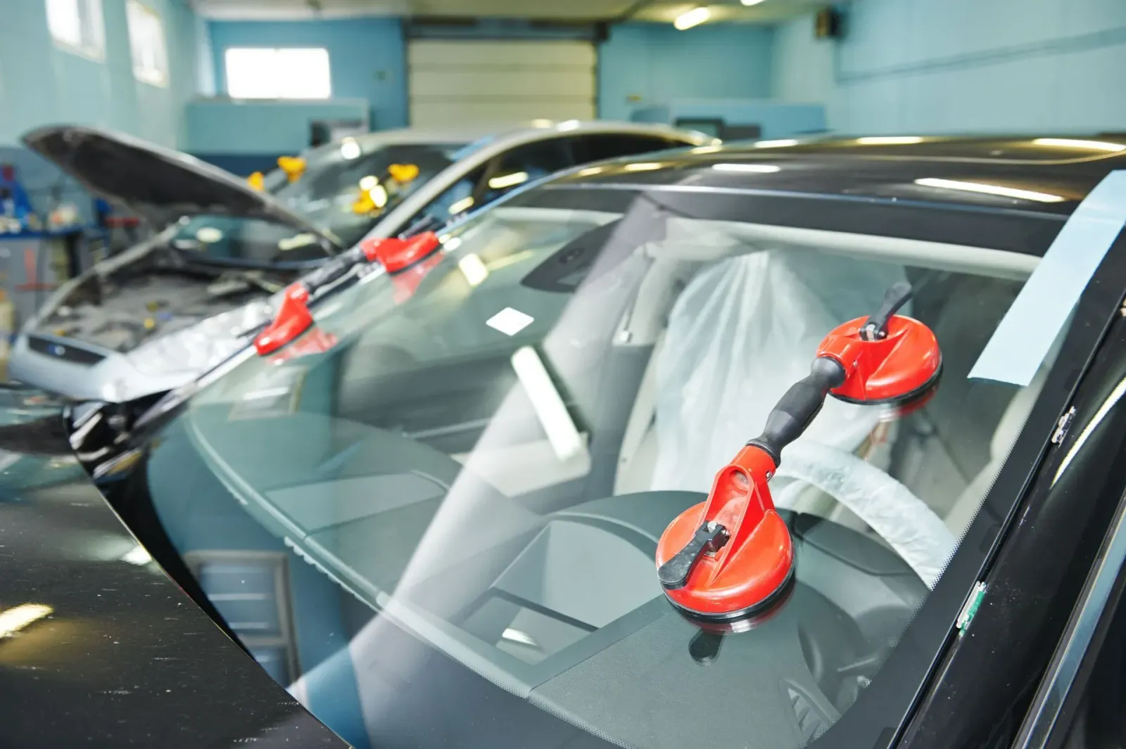 Car windshield with red suction cups in a repair shop.