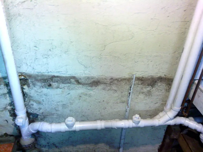 PVC waste line run along a basement wall