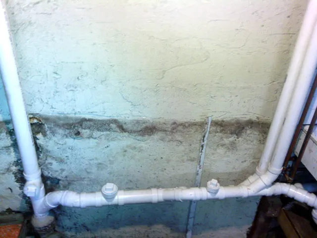 PVC waste line run along a basement wall