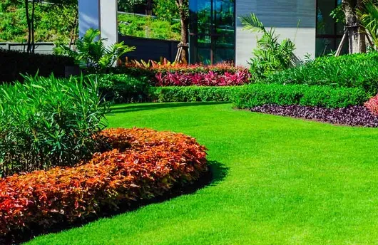 Bright green landscaped garden with colorful flower beds beside a modern building