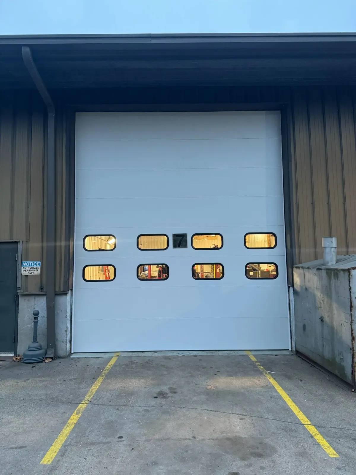 A white garage door with a lot of windows is sitting in front of a building.