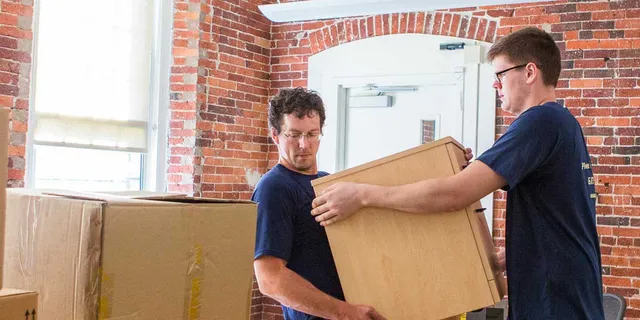 Two movers carrying a cabinet during an office relocation