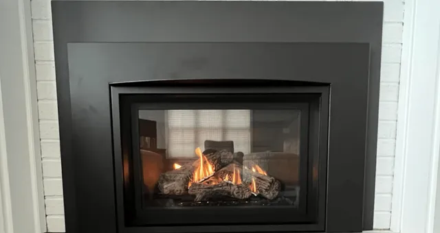 Gas fireplace insert installed in a white brick fireplace in Westbrook ME by the Frechette Chimney Sweeping Team