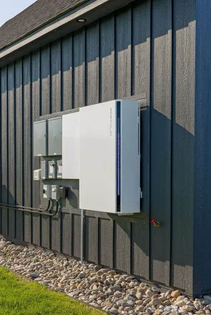 Wall-mounted white utility cabinet and electrical equipment on a dark exterior building wall.