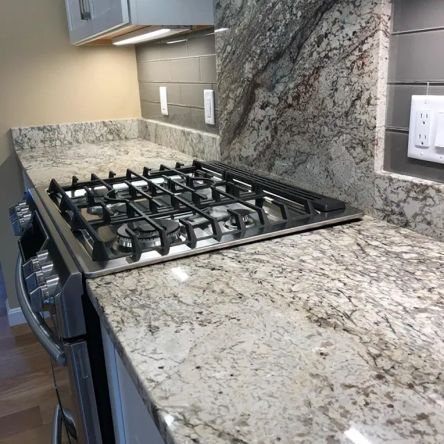A stove top oven is sitting on top of a granite counter in a kitchen.