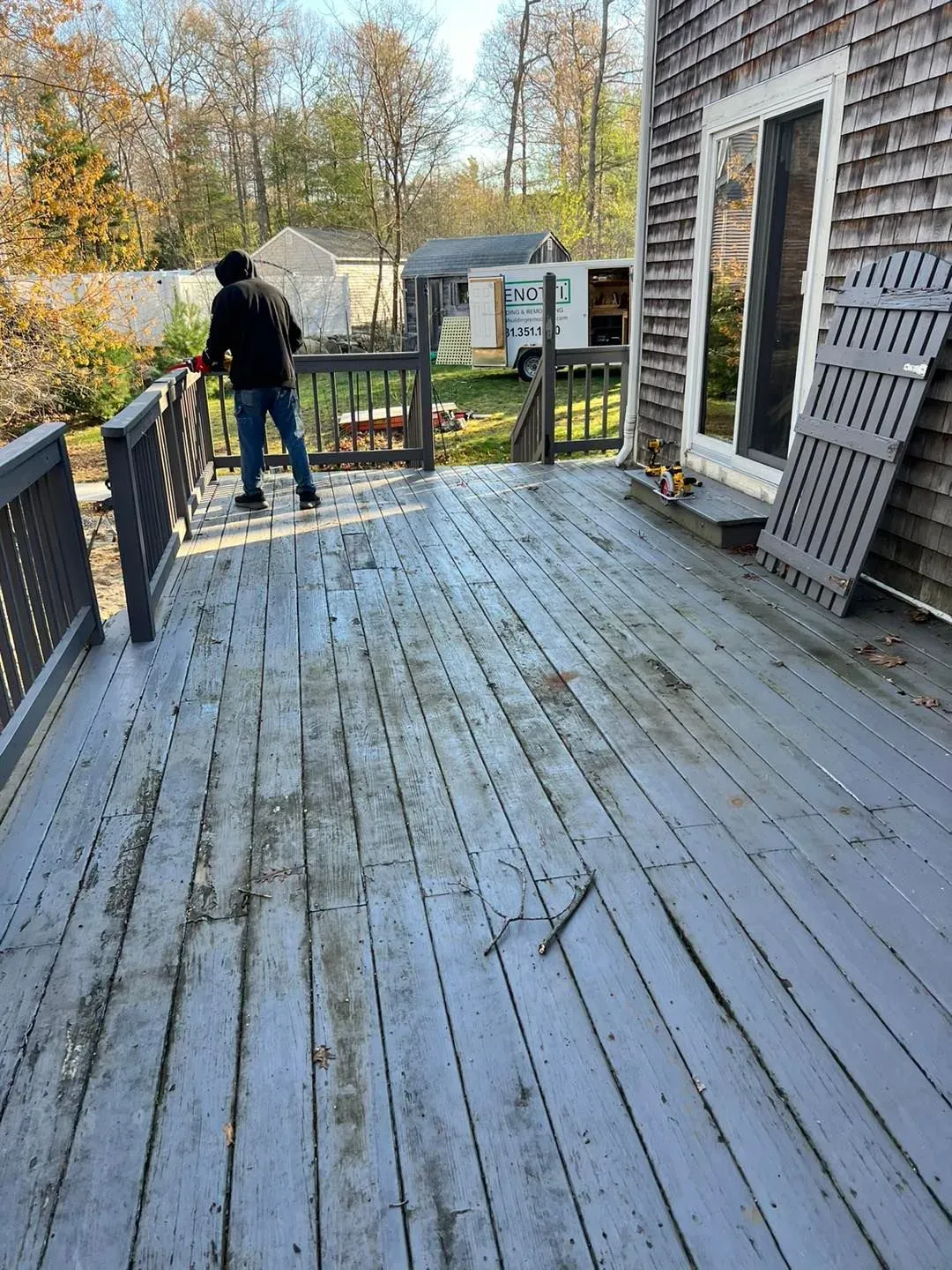 a man is standing on a wooden deck in front of a house .