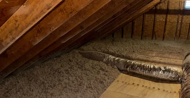 An attic with a metal pipe sticking out of the floor.