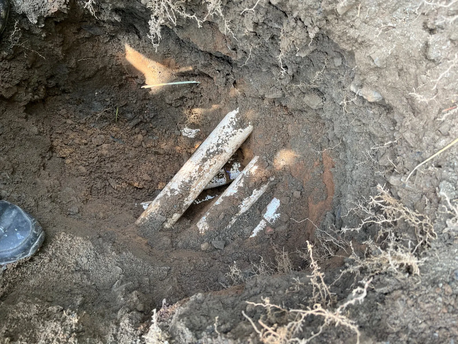 Excavated pool return line showing cracked underground pipes — leak source located