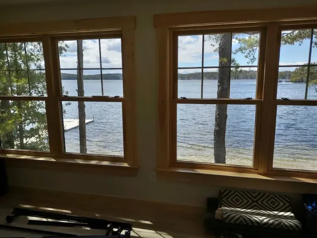 A living room with two windows looking out to a lake