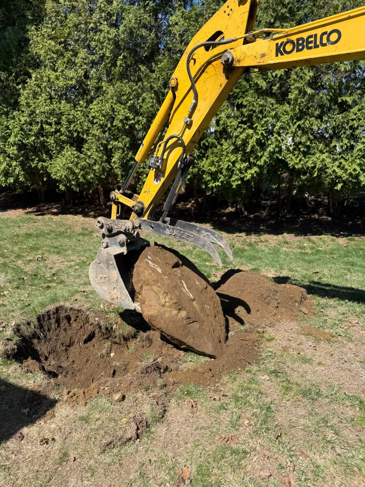 Excavator bucket digging soil for a landscaping installation