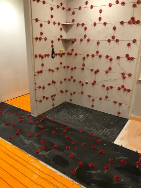 Indoor climbing wall with red holds and black-and-orange padded flooring.