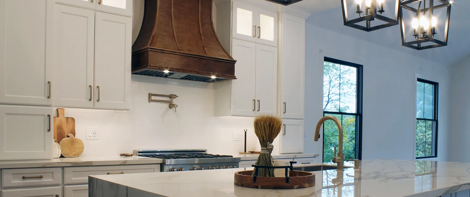 Luxury kitchen remodel in Marblehead featuring a large marble waterfall island, custom white cabinetry, and designer pendant lighting.