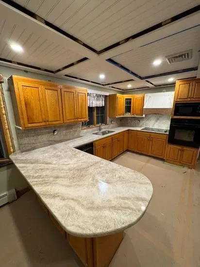 Custom asymmetrical rounded peninsula edge completed for a Taj Mahal Quartzite Kitchen project.