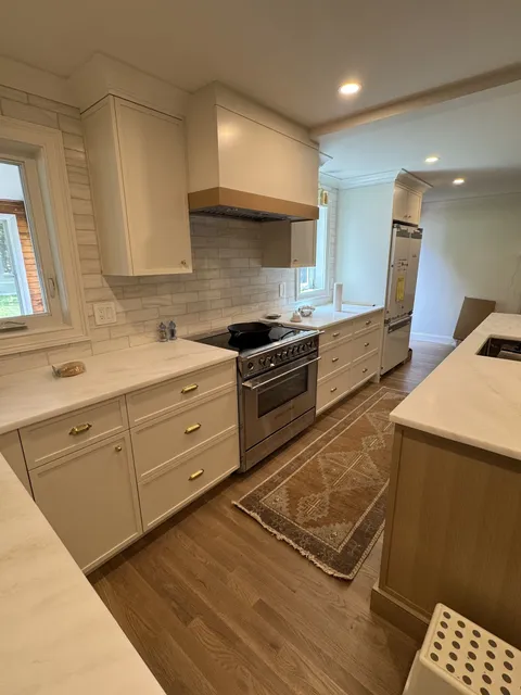 Custom cream kitchen cabinets with wood range hood and brass hardware