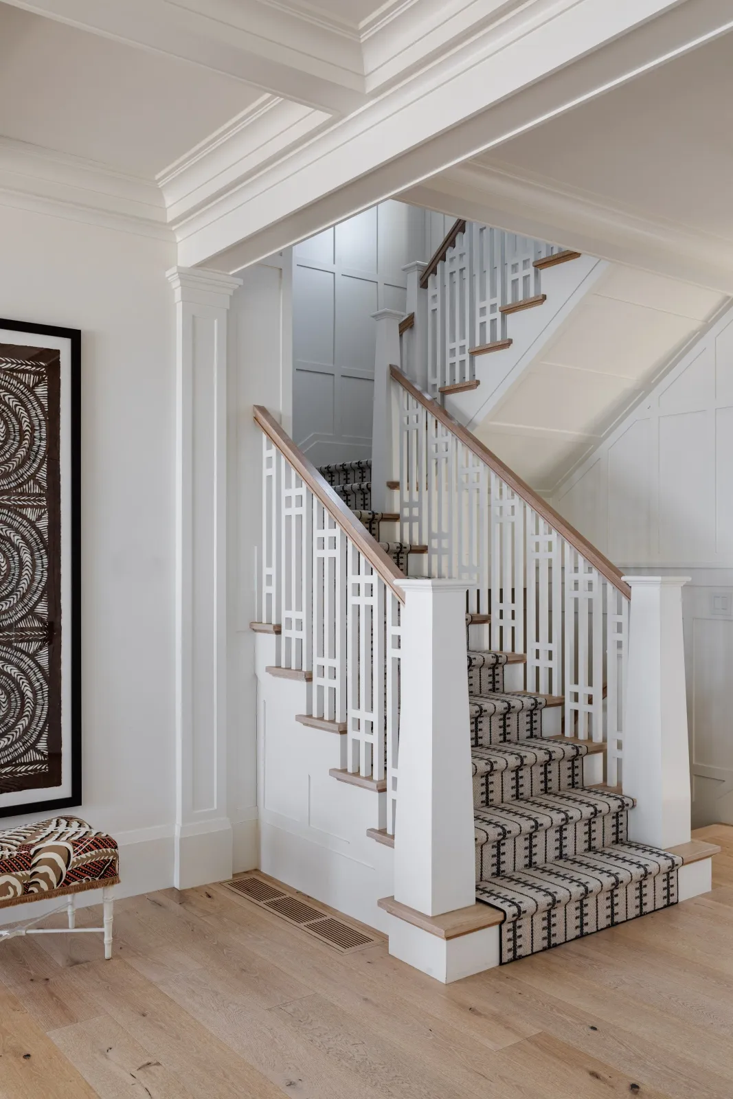 Hardwood floor refinishing in a Pembroke home with an interior staircase featuring white railings, a wooden handrail, carpeted steps, and framed artwork on the wall.