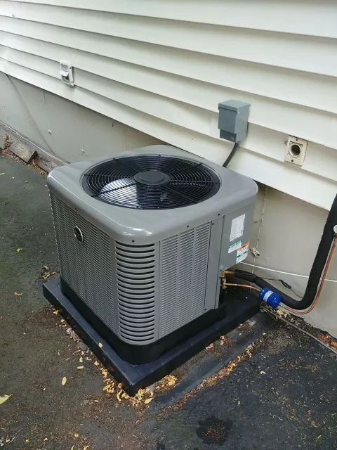 An air conditioner is sitting on the side of a house.
