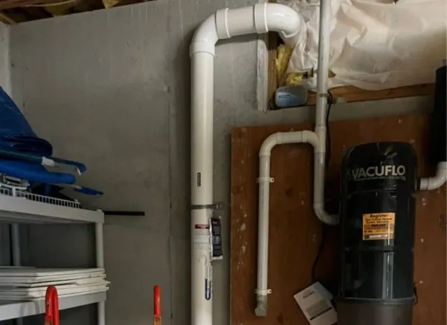 A vacuum cleaner is mounted to the wall in a garage.