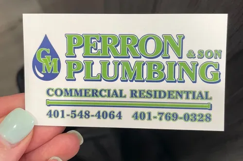 A person is holding a business card for GM Perron & Son Plumbing