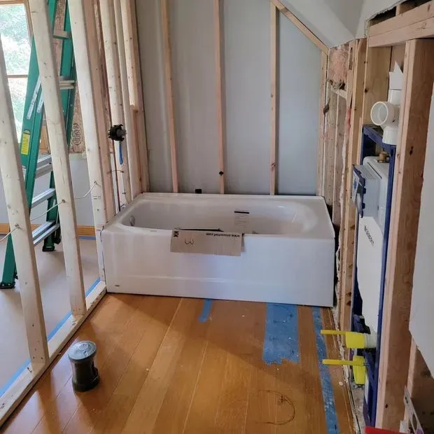 Bathtub installed in a partially renovated bathroom with exposed studs and construction materials