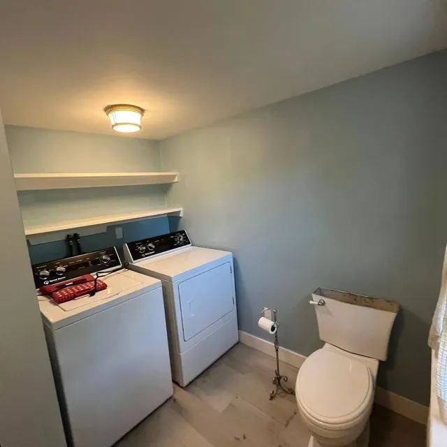 A laundry room with a washer and dryer and a toilet.