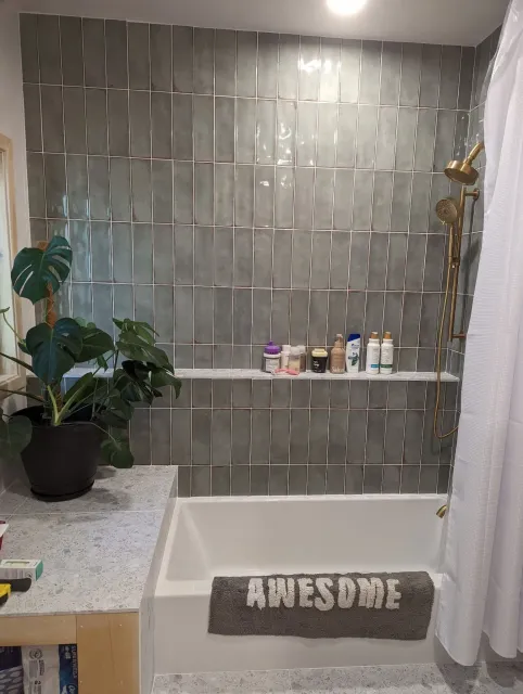 A bathroom with a tub , shower , and a rug that says awesome.