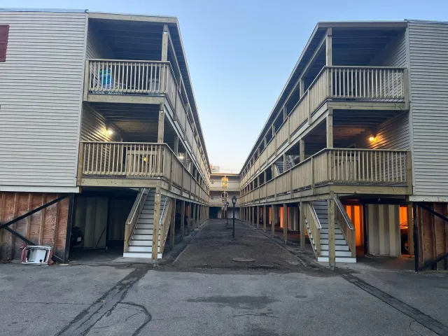 The Milestone Condominium decks. Two connected multi-story buildings with wooden balconies, stairways, and a center pathway.