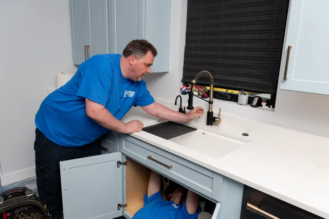 Phillips Plumbing technician working under a kitchen sink