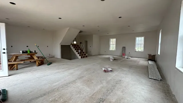 A large empty room with a picnic table and stairs.