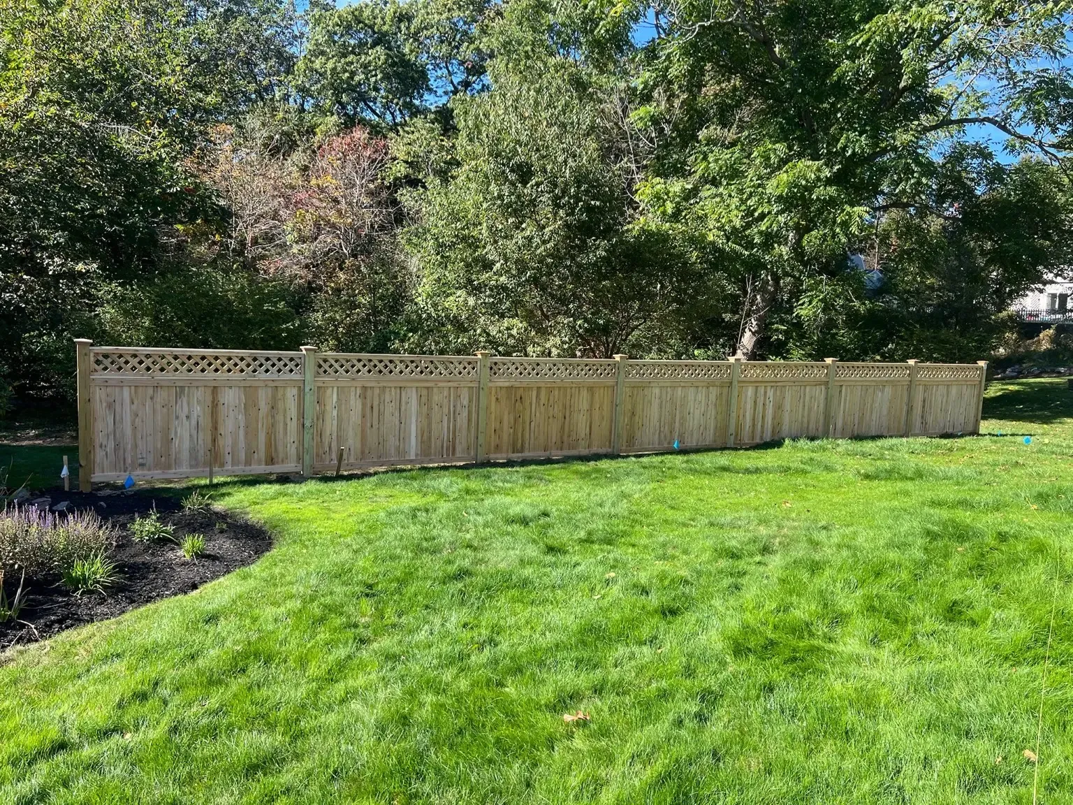 Wood privacy fence with lattice top installed across a landscaped backyard