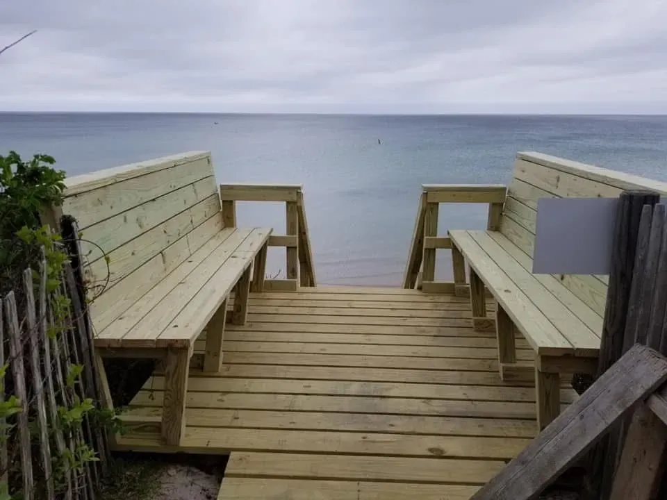 A wooden dock with benches leading to the ocean