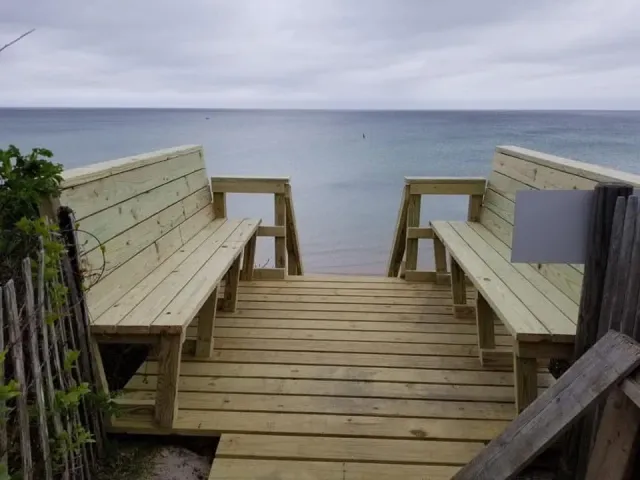 A wooden dock with benches leading to the ocean