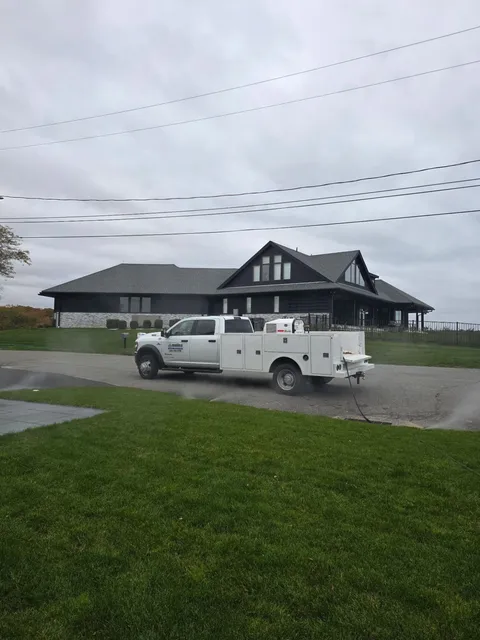 White work truck parked in front of a modern house on a cloudy day.