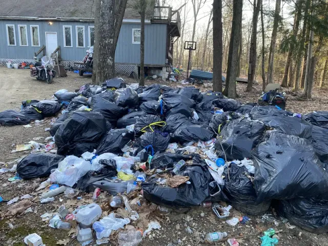 Yard covered with piles of trash bags and debris