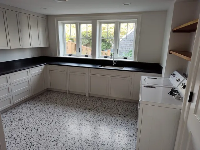 Kitchen with white cabinets, dark stone countertops and bright windows