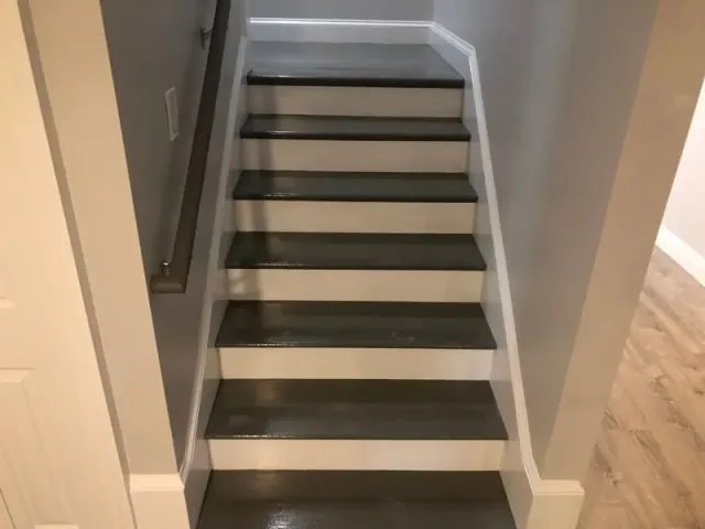 Gray painted wooden stairs with white risers and baseboards.