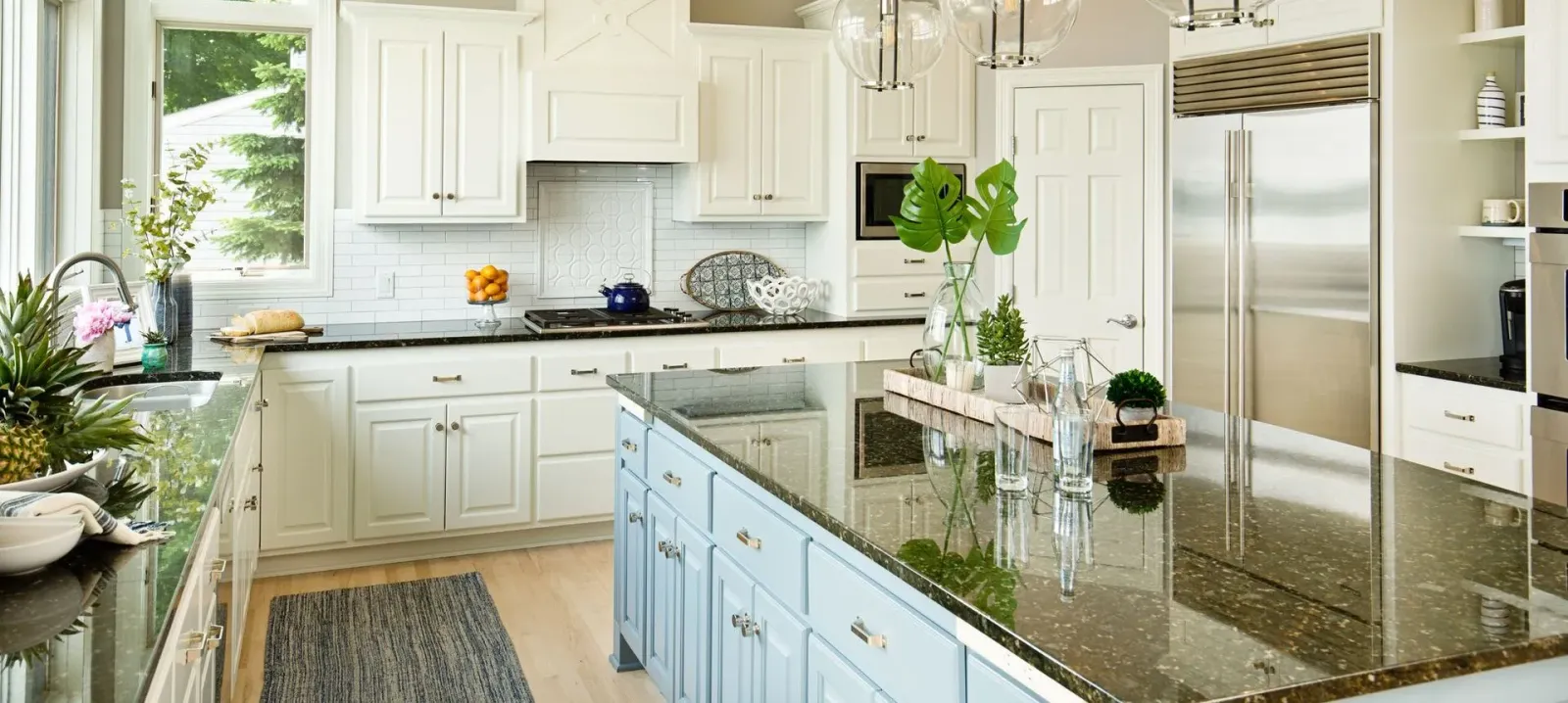 A kitchen with white cabinets , black granite counter tops , and stainless steel appliances.