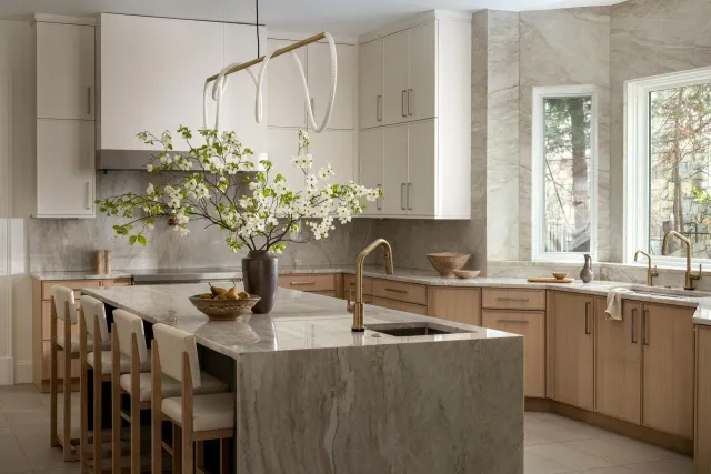 Modern kitchen with island, wood cabinetry, pendant lights, and a vase of flowering branches