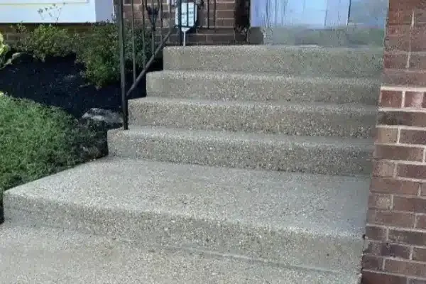 After: Concrete steps leading to a front door, flanked by grass and a railing on one side.
