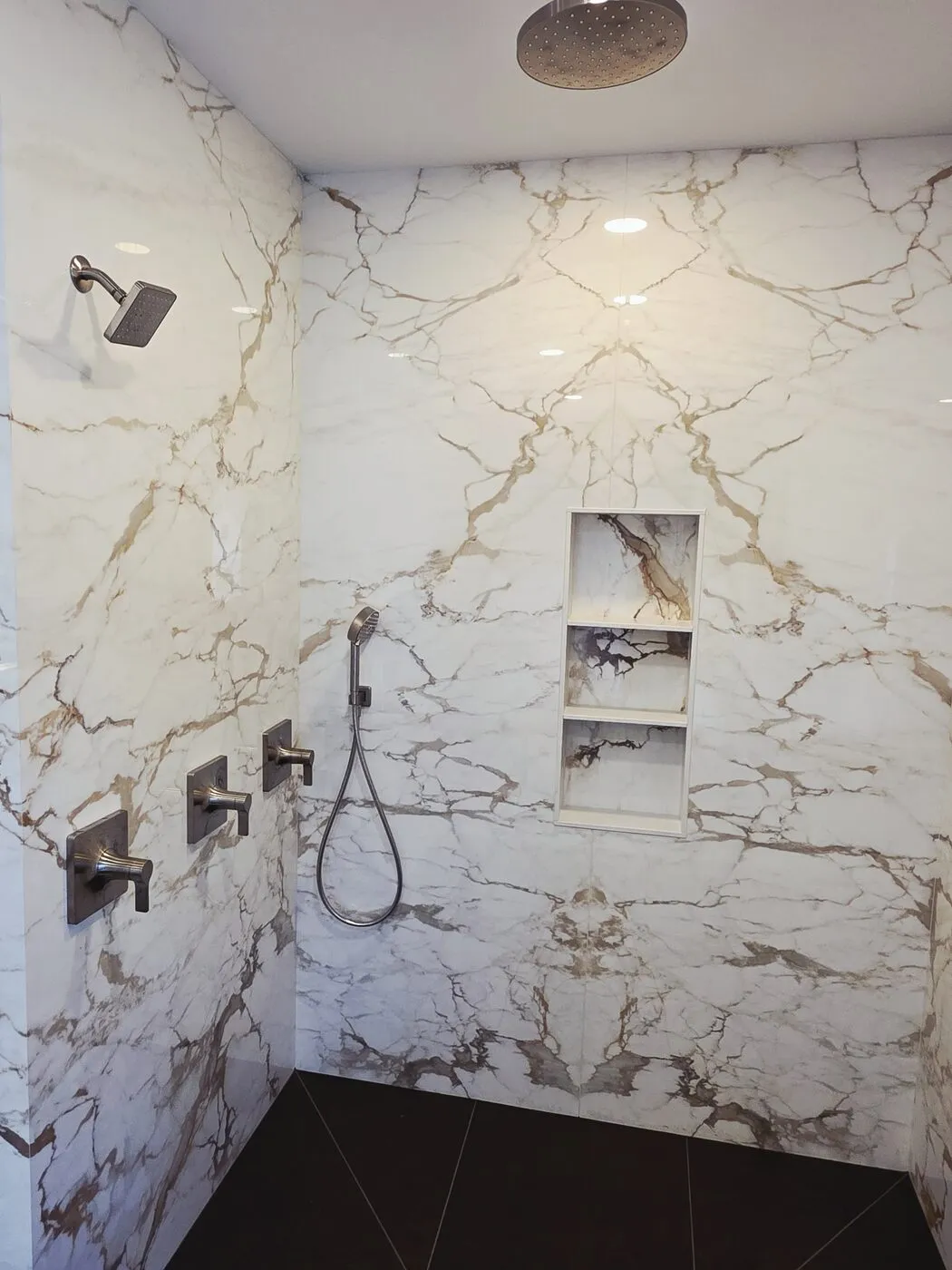 Marble walk-in shower with a rain head, hand shower and recessed niche